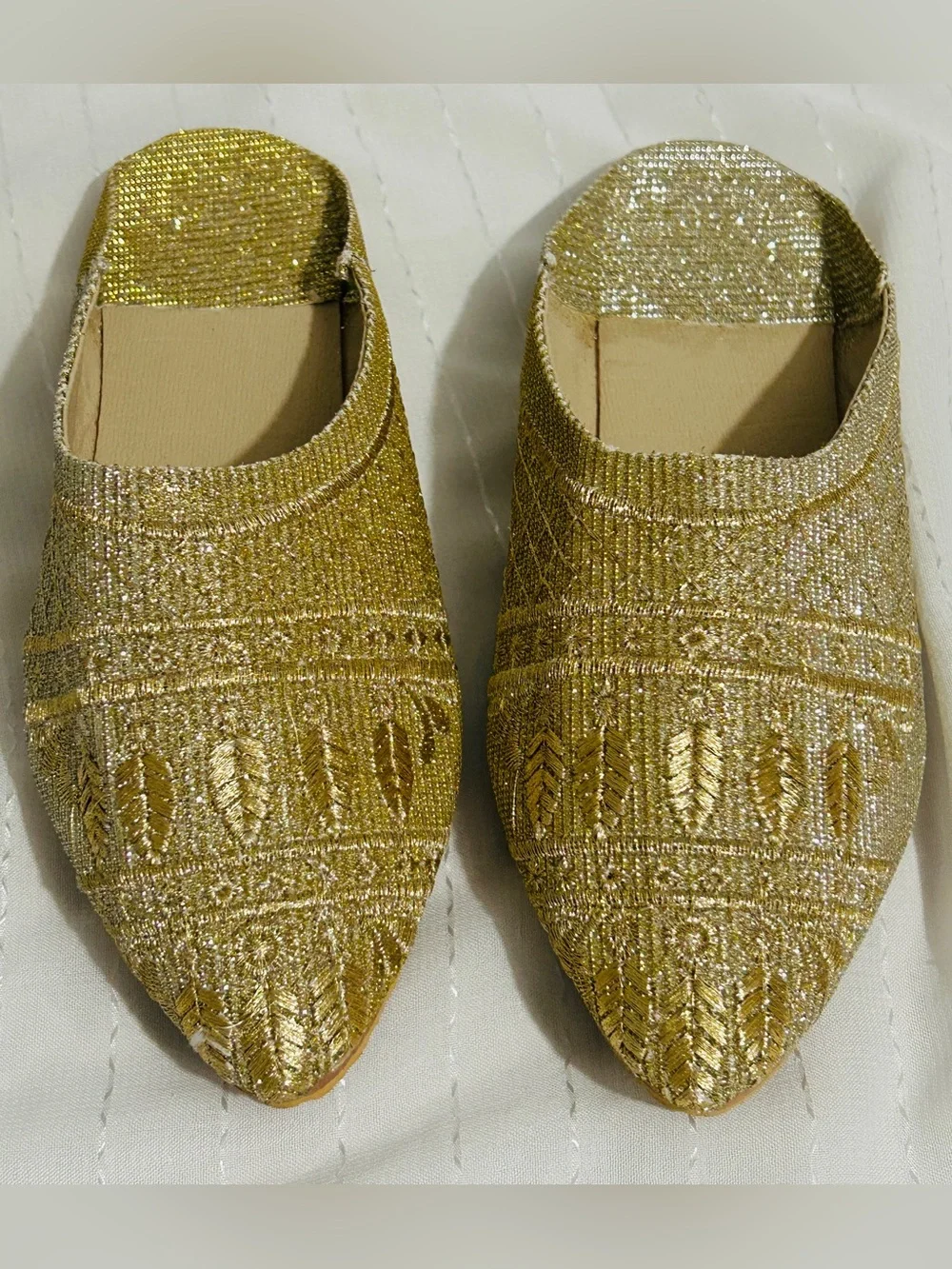 Moroccan babouche slippers adorned with intricate embroidery and a pointed toe.