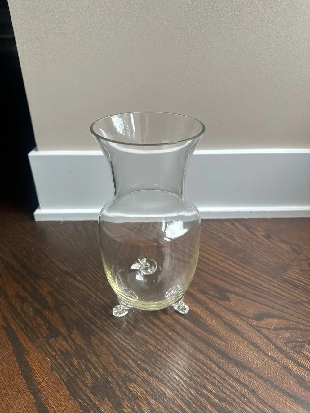 Clear glass vase featuring a wide mouth and is elevated on three small legs