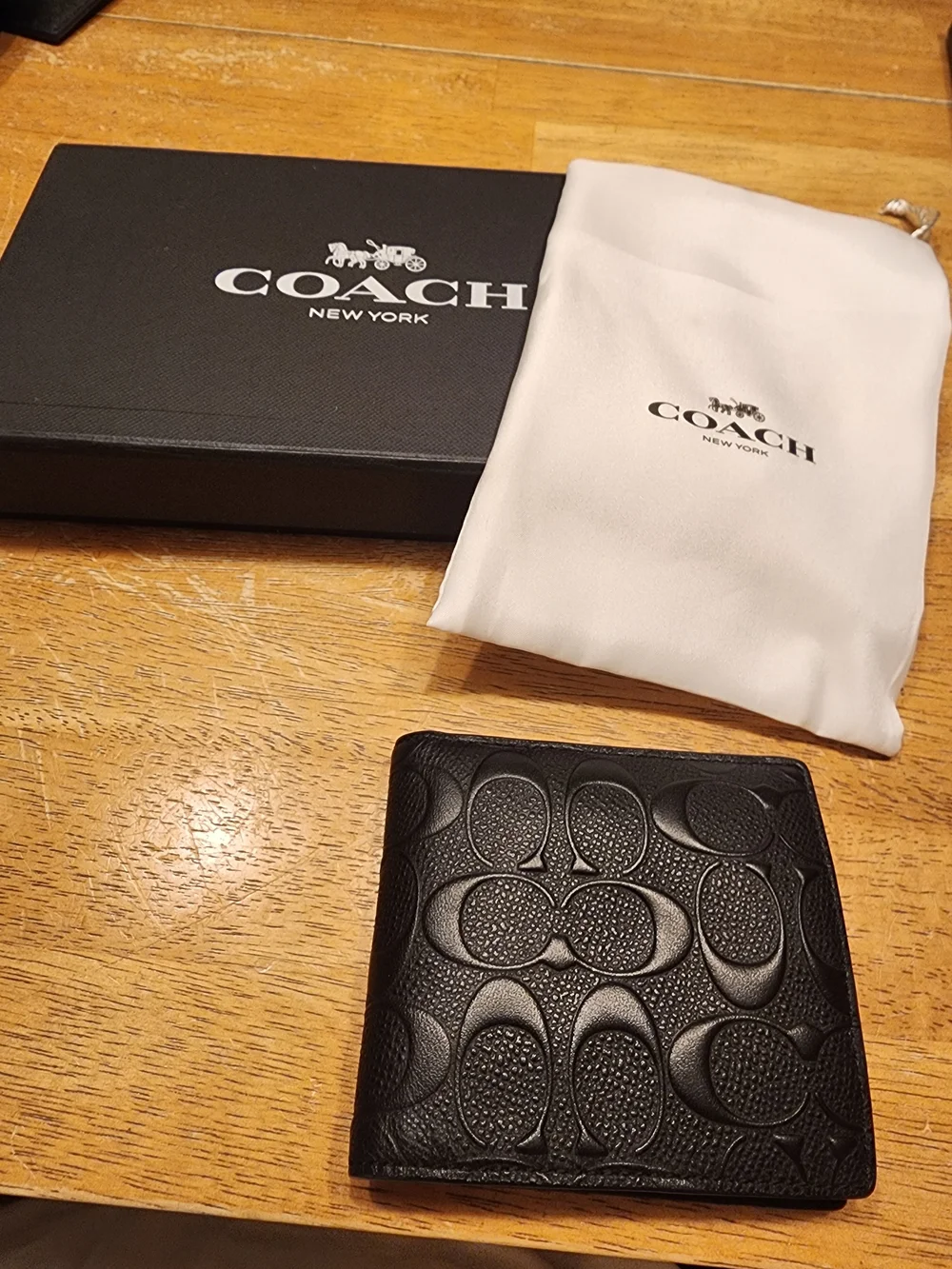 black Coach 3-in-1 wallet featuring the brand's iconic debossed signature pebble