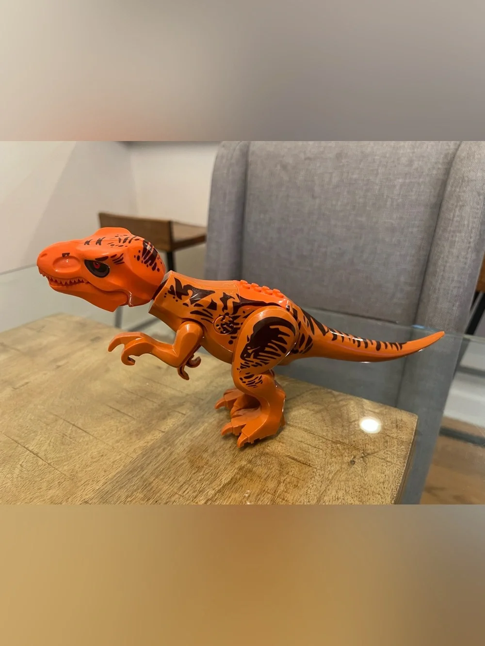 orange-and-brown molded plastic Tyrannosaurus Rex dinosaur makes noise building